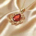 Primo piano di un ciondolo vintage a goccia con pietra rossa e dettagli in filigrana. - Collana / Rosso