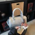 Trendy silver metallic cylindrical shoulder bag with cute plush bow keychain for daily use. - Silver