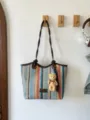 Detailed view of colorful straw tote bag with braided handles and cute bear pendant. - Style 2 (Rainbow Stripes) / With Pendant / Brown