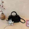 Close-up detail of a minimalist black women handbag with a stylish silver star keychain charm. - With Pendant / Black