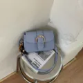 Chic light blue denim crossbody bag with metal buckle flap and stylish beaded charm detail. - With Pendant / Blue