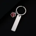 Close-up detail of stainless steel keychain featuring a red glitter paw pendant and blank metal tag. - Rectangle Bar (50X12mm) with Red Glitter Dog Paw / Silver