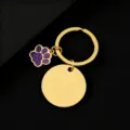 Detailaufnahme eines goldenen Metallschlüsselanhängers mit runder Plakette und Pfoten-Anhänger. - Gold Basis Violette Pfote / 30mm Rund