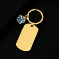 Close-up of gold metal keychain with blank dog tag and blue glitter paw charm detail. - Military Tag (50X28mm) with Blue Glitter Dog Paw / Gold
