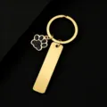 Gold metal keychain detail with glitter paw charm and blank rectangular plate for engraving. - Rectangle Tag with Black Glitter Dog Paw / 50x12mm / Gold