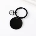 Detailed view of the black stainless steel keychain featuring a round disc and heart seed pendant. - 30mm Circle And Heart Charm Key Ring / Black