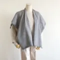 Grijs gebreide cape detail toont zachte woltextuur en elegante drapering voor de winter. - 140x80cm / Grijs