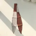 Vue détaillée d'un foulard en soie étroit à pois chic, idéal pour sublimer vos chemises. - 120x10cm / Marron
