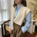 Primer plano de un chal de punto elegante y moderno drapeado sobre una bonita camisa azul. - Beige