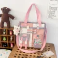 Detail view of pink canvas tote bag with multiple pockets, charms and clear window. - Bag + Pom-Pom Badge / Light Purple