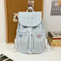 Light blue casual backpack detail showcasing front drawstring pockets with cute beads and straps. - Blue