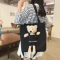 Vista detallada de un bolso tote de lona negra con un bolsillo de peluche de osito lindo adjunto. - Con Colgante de Oso / Negro