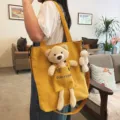 Detalle del bolso tote de lona amarilla con lindo osito de peluche 3D y mini colgante accesorio. - Con Colgante de Oso / Amarillo