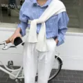 Detail view of a solid white knit shoulder cape worn over a blue striped shirt, stylish. - Milk White