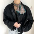 Vue rapprochee et detaillee d'un foulard en soie imprime avec une veste en cuir noir. - Vert