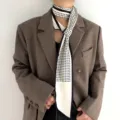 Gros plan sur un foulard en soie à pois noirs et blancs élégamment noué autour du cou. - Blanc