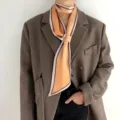 Vue détaillée du foulard en soie chic à pois orange élégamment assorti avec un blazer marron. - Or