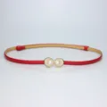 Detailed view of the slim red leather belt featuring elegant gold shell and pearl buckle design. - Red
