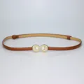 Detailed view of a elegant brown thin leather belt featuring a chic pearl shell buckle. - Camel