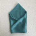 Detailed shot of the elegant teal silk scarf, showing smooth fabric texture and neat folding. - Bean Green