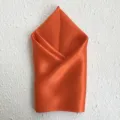 Detailed view of a premium orange silk square scarf neatly folded, elegant accessory for autumn. - Orange