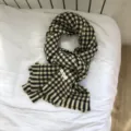 Detailaufnahme eines klassischen karierten Strickschals mit Fransen für den Winter. - Schwarz Weiß Gelb Hahnentritt