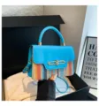 Detailed closeup of stylish blue handbag with colorful woven straw and metal lock design. - Blue