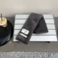Dark grey plush winter scarf detail view featuring stylish aesthetic fabric labels for cozy warmth. - Gray