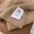 Detailaufnahme eines Strickschals mit Vintage-Stoffetikett, weich dick für warme Wintertage. - Camel