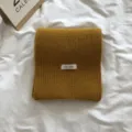 Vue rapprochée détaillée d'une écharpe d'hiver en tricot jaune moutarde avec petite étiquette. - Curcuma