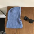 Close-up of blue knit balaclava hood scarf with snap button on wooden table. - One Size / Blue