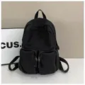 Detailed view of the black canvas backpack featuring front zipper pockets and top carry handle. - One Size / Black