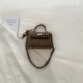 Stylish brown leather top handle handbag with metal lock and shoulder strap for women daily use. - With Pendant / Brown