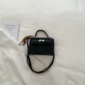 Black minimalist style handbag featuring a classic lock closure and elegant handle details. - With Pendant / Black