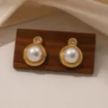Detailopname van prachtige gouden oorknopjes met parels en kristal op een houten blok. - Ronde Parel (E2251)