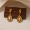 Detailopname van vintage gouden druppelvormige oorbellen met parel en fijne textuur. - Ovale Ingelegde Parel (E2261)