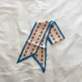 Gros plan détail du foulard twilly en soie mince de style coréen avec bordure bleue. - Bleu