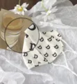 Weisser Sonnenschutz Gesichtsmaske mit schwarzem Buchstabenmuster und Eisseide Stoff. - Buchstabe D