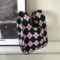 Nahaufnahme der gestrickten Blumentasche mit einem süßen rosa und schwarzen Blumenmuster. - Handtasche Stil / Violett