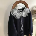 Close-up detail of a dark blue sweatshirt paired with a white lace embroidered fake collar. - Large Shield Floral