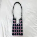 Detailansicht des rosa schwarzen gestrickten Blumenmusters und Schulterriemens der Tasche. - Rucksack-Stil / Lila Floral