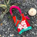 Gestrickte Umhängetasche mit buntem Blumenmuster, grüner Kette und stilvollen Produktdetails. - Original Schultergurt-Set / Rot