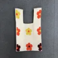 Detailaufnahme einer gestrickten Blumen-Handgelenktasche mit weicher Textur und bunten Mustern. - Khaki