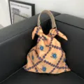 Detailansicht der stilvollen blumigen Stofftasche mit elegantem hellem Griff und Knoten. - Orange