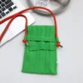 Grüne gestrickte Mini Handytasche mit orangefarbenem Gurt, feine Strickstruktur Detail. - Sattes Grün
