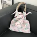 Detailansicht einer schicken Handtasche aus Stoff mit Blumenmuster und Ledergriff. - Lotosrosa