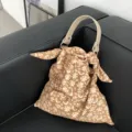 Detailansicht der stilvollen braunen Stofftasche mit Blumenmuster, hellem Griff und Knotendesign. - Kurkuma