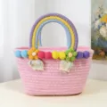 Cute pink woven handbag with rainbow handle and colorful pom-poms, perfect for beach use. - L / Pink