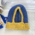 Blue and yellow colorblock knitted balaclava cap detail showing woolen texture and button accent. - Blue