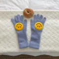 Vue en gros plan de gants en tricot bleu clair avec de jolis écussons smiley jaunes. - Bleu ciel